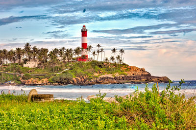 Lighthouse on beach by sea against sky