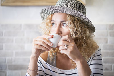 Close-up of woman wearing hat drinking coffee