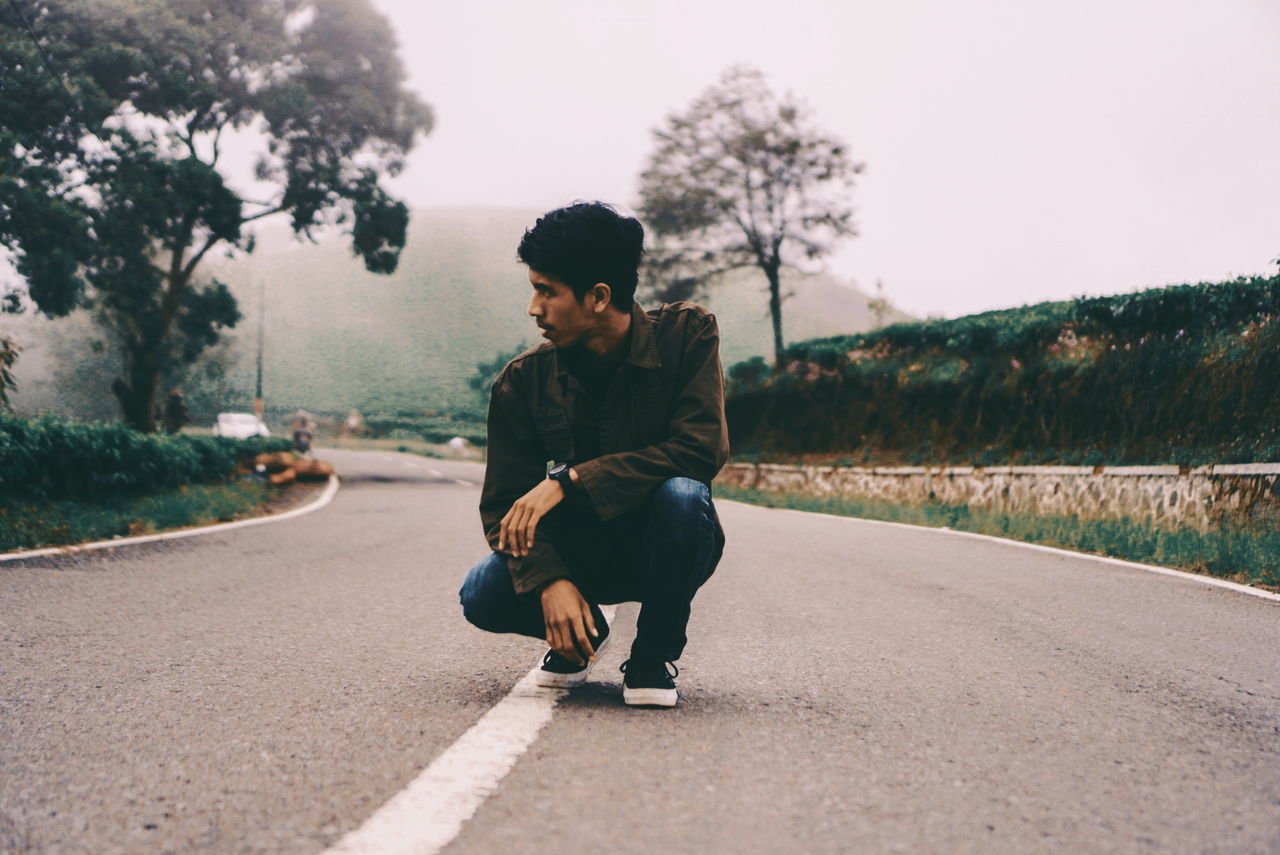 FULL LENGTH OF YOUNG MAN SITTING ON ROAD