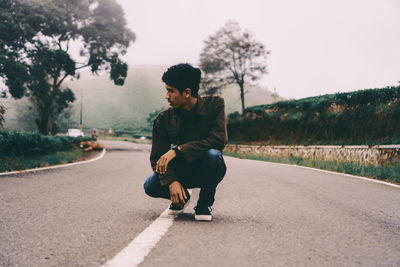 Full length of man sitting on road