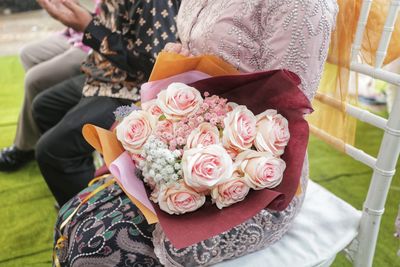 Midsection of woman holding rose bouquet