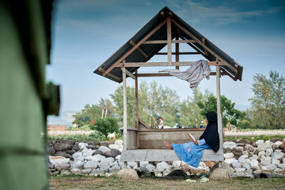 Little girl sitting and reading a book at a wooden gazebo outdoors