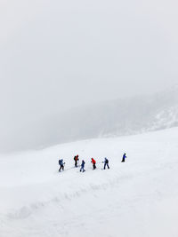 People on snowcapped mountain against sky