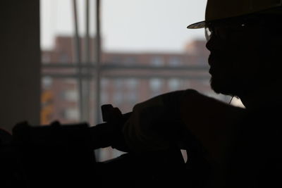 Close-up portrait of silhouette man holding window