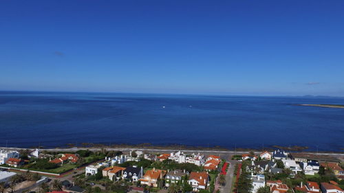 High angle view of sea and buildings against clear blue sky