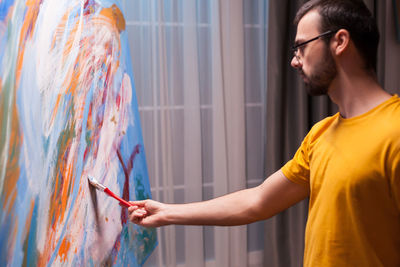 Side view of man against graffiti wall