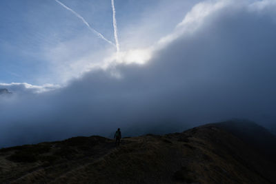 Man standing on mountain against cloudy sky