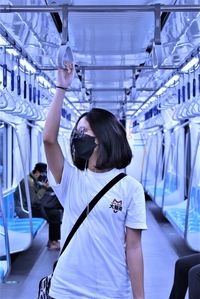 Young woman with arms raised standing in corridor