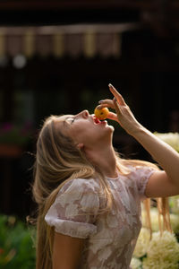 Young woman eating fruits in the garden against the background of flowers