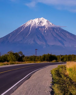 Road by snowcapped mountains against sky