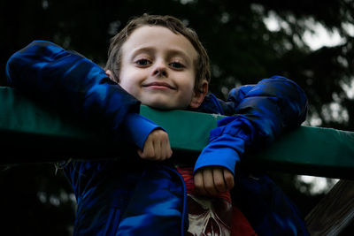 Portrait of smiling boy hanging from railing