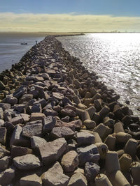 Surface level of stones on beach against sky