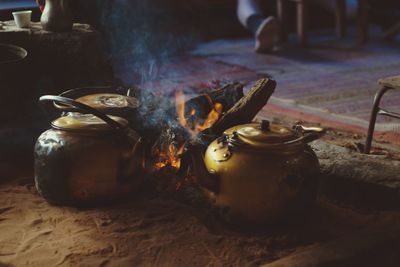 Close-up of teapots by bonfire