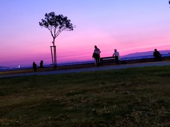 Silhouette people on field against sky during sunset