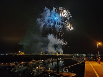 Firework display in city against sky at night