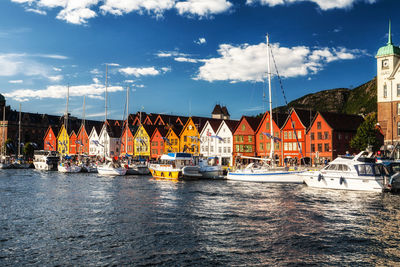 Sailboats moored in sea against sky in city