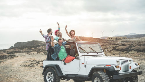 People on vehicle against sky