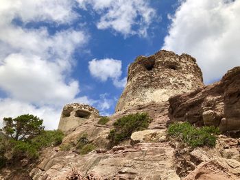 Bottom view of the rock formation against the sky with typical ancient sardinian buildings