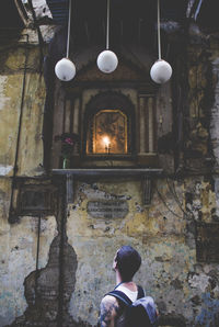 Rear view of man standing against weathered wall