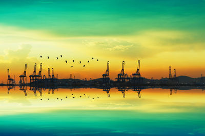 Birds flying over lake against sky during sunset