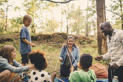 Multi-ethnic family playing with skewers at picnic spot in park