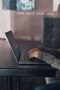 Woman working remotely on her laptop computer managing her work sitting at the table in a cafe