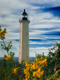 Lighthouse by sea against sky