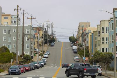 Cars on street in city against clear sky