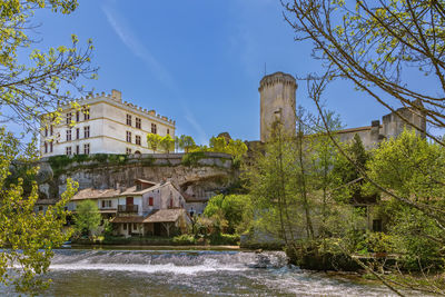 Buildings by river against sky