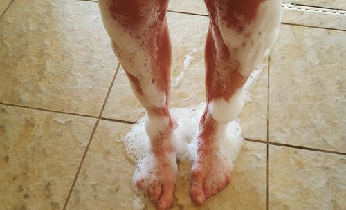 Low section of man standing on tiled floor