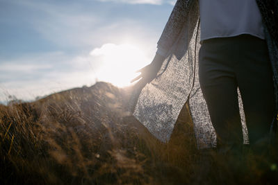 Midsection of woman standing on field against sky