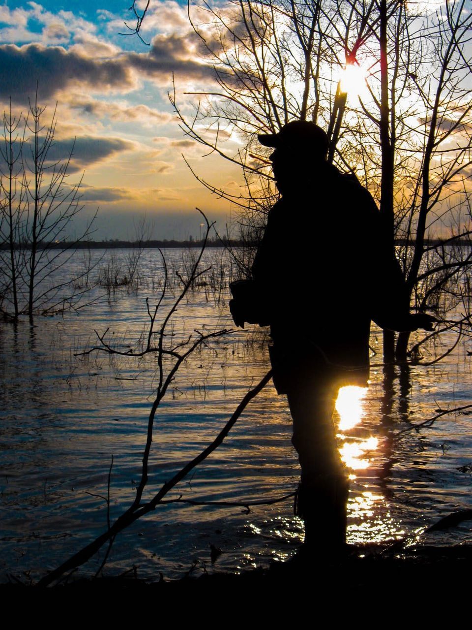 SILHOUETTE MAN STANDING BY LAKE AGAINST SKY