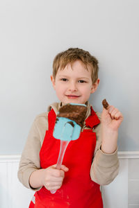 Portrait of smiling boy standing against white wall