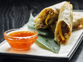 Close-up of crunchy stuffed rolled pancakes in plate on table