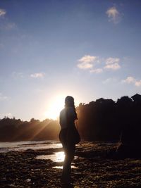 Silhouette woman standing on beach during sunset