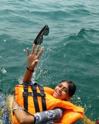 High angle view of woman wearing life jacket swimming in sea