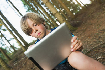 Boy using digital tablet in forest