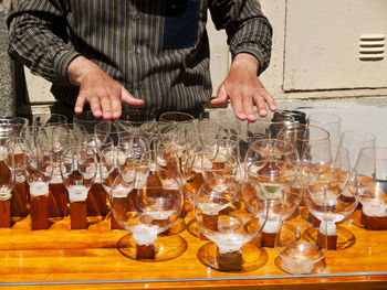 Midsection of man preparing food in glass on table