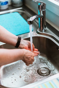 Close-up view of woman washing hands with soap and water from faucet