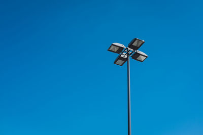 Low angle view of telephone pole against clear blue sky