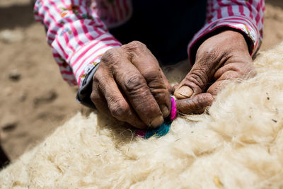 Cropped hands of man weaving rug