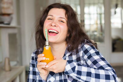 Portrait of smiling woman holding juice sitting at cafe