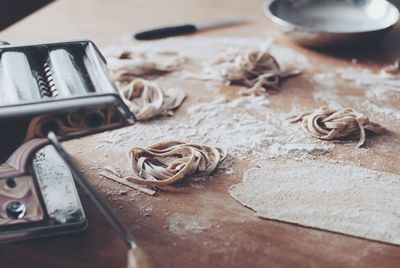 High angle view of homemade tagliatelle with pasta maker on table