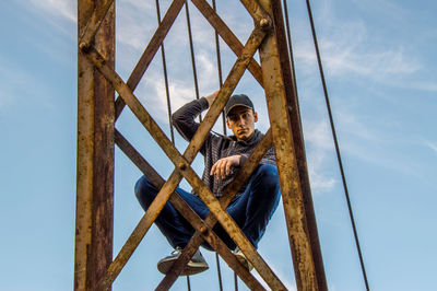 Full length portrait of teenage boy on rusty built structure against sky