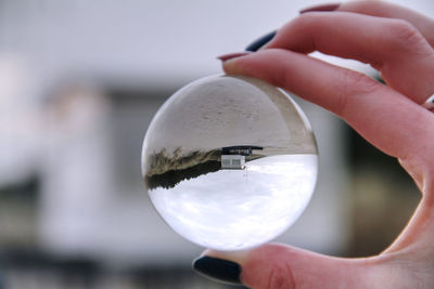 Close-up of human hand holding crystal ball outdoors