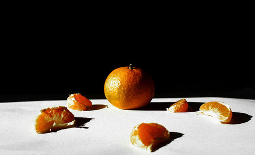 Close-up of orange fruits on table against black background