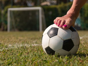 Low section of woman playing soccer ball on grassy field