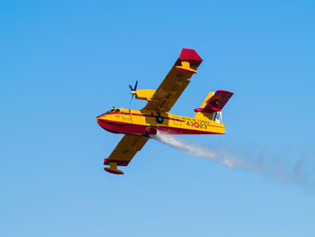 Low angle view of airplane flying against clear blue sky