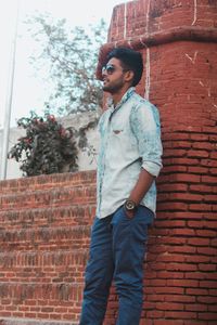 Young man standing against brick wall