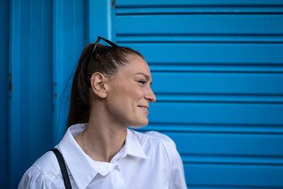 Smiling young woman against blue wall